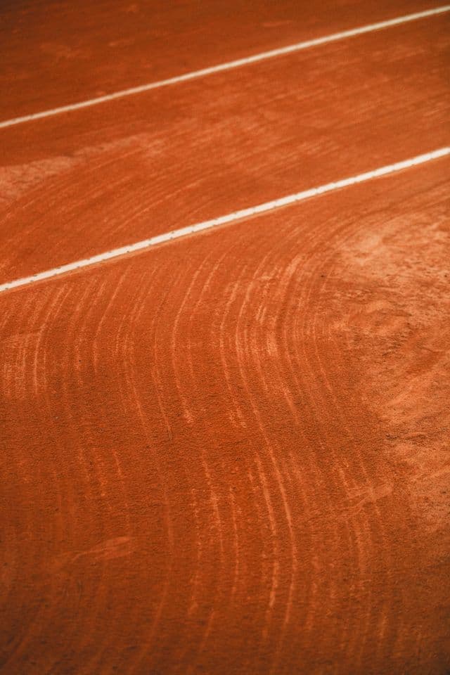 Sunlit red-clay tennis court